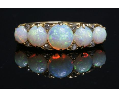 A Victorian five stone opal carved head ring,with five graduated circular cabochon opals, all claw set to a carved head, with