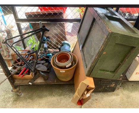 Shelf of largely hand tools, part of a bike frame, bench grinder, pots and shoe lasts