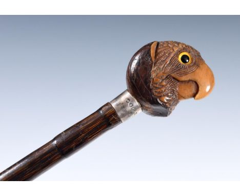 A 19th century walking stick, with coquilla nut handle, carved in the form of a parrot with glass eyes, with silver mount, on