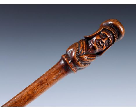 An early 20th century folk art walking stick, with carved handle, in the form of a figure with medieval guard, shaft carved w