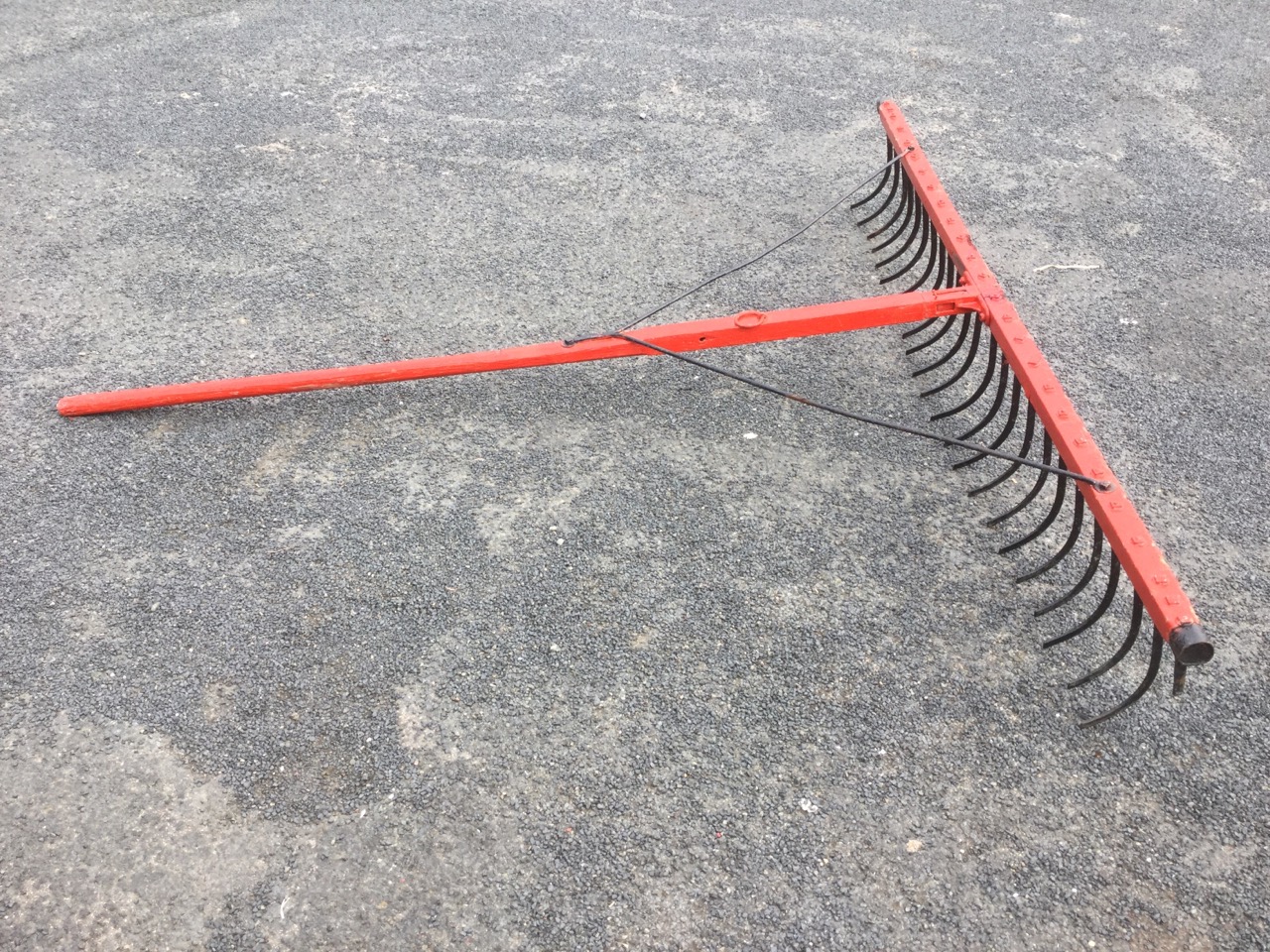 A large old harrow, with wood and curved blades, in recent paintwork.