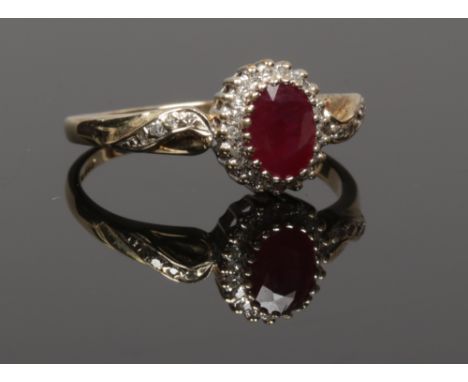 A 9ct gold ruby and diamond ring with diamond set shoulders, size T.