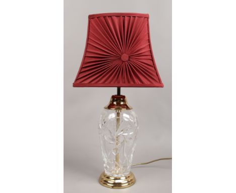 A cut glass and brass effect table lamp with red shade.