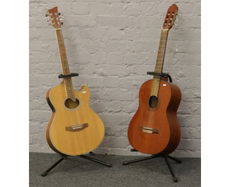 A Jay Turser semi acoustic guitar on stand, along with a Valencia acoustic guitar on stand in need of restoration.