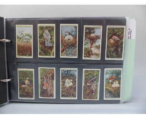 A collection of cigarette cards in three albums, includes Wills & Players, sets include Ships Badges, Romance of the Heavens,