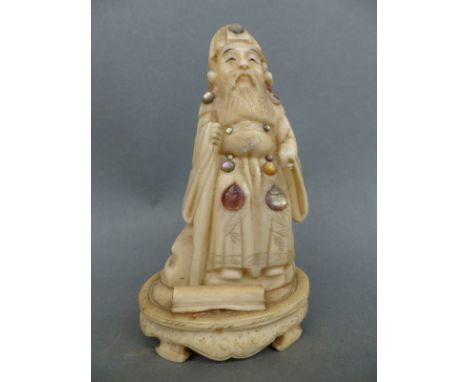 A 19thC carved ivory figure of a scholar with mother of pearl cabochons, 8cm tall