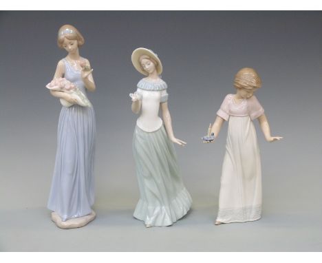 Three Nao figurines comprising a girl with bouquet of roses, a girl with butterfly and a girl with candlestick, tallest 25cm