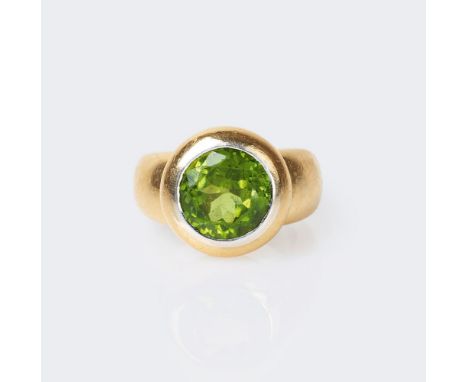 Peridot-Ring. 18 kt. GG mit WG. In WG-Zargenfassung der Peridot im Rundschliff ca. 3,30 ct. (9,5 x 6 mm, Abrieb). Innen Spann