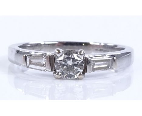 An 18ct white gold 3-stone diamond ring, central diamond approx 0.24cts, with tapered baguette-cut diamond shoulders, size K,