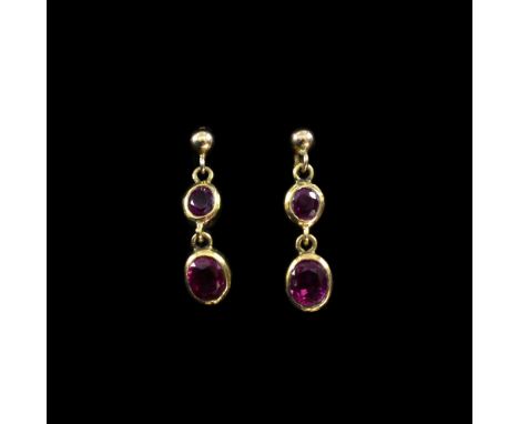 A pair of ruby drop earrings, each set with  two graduated oval-cut rubies in a gold rub-over setting, mounted in yellow meta
