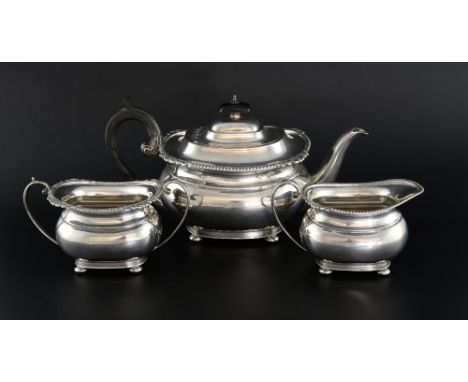 Modern silver three piece tea service comprising teapot, cream jug and sugar bowl, with gadrooned and shell moulded rim on bu