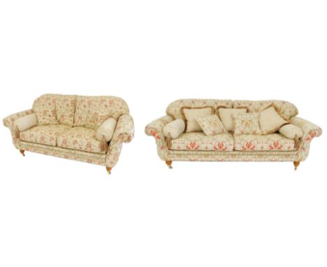 A large deep seated sofa, upholstered in gold, red and silvered pattern fabric, on turned and reeded legs with brass castors,