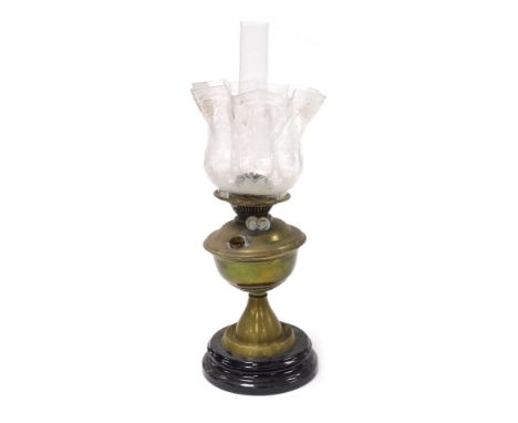 An early 20thC brass oil lamp, raised on a glass socle, with glass chimney and floral etched frilled glass shade, 53cm high.
