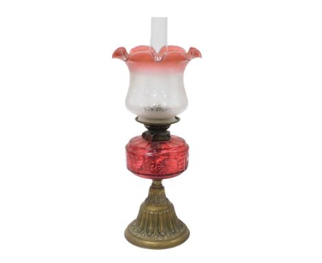 A late 19thC Young's brass oil lamp, with a cranberry glass reservoir, glass chimney and frosted to cranberry etched glass sh