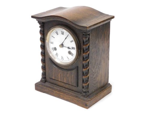 An early 20thC oak cased mantel clock, circular enamel dial bearing Roman numerals, eight day movement with coil strike, the 