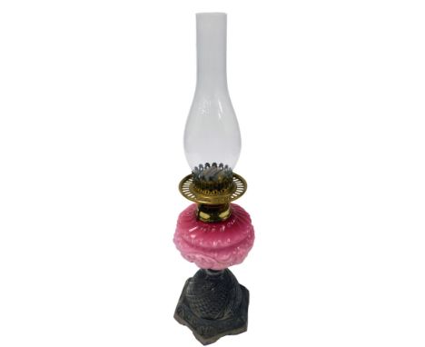 A late 19thC Young's number two cast iron oil lamp, with a pink opaline glass reservoir, moulded with scrolling leaves, with 