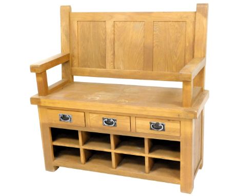 A light oak settle, with a panelled back, plain arms above an arrangement of three drawers and eight recesses, on stiles, 106