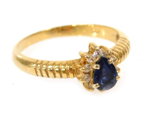 A lady's dress ring, set with a blue pear shaped stone, in a surround of white stones, in yellow metal, stamped 14ct, size M,