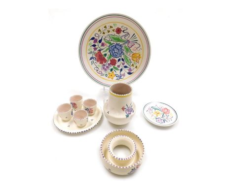 A group of 20thC Poole pottery, traditionally painted with flowers, comprising four egg cups on stand, circular posy holder, 