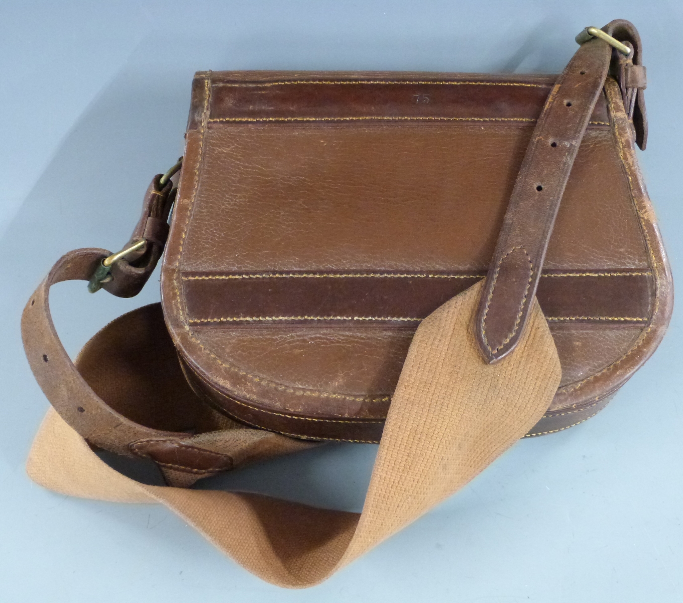 A vintage canvas and brown leather shotgun cartridge bag.