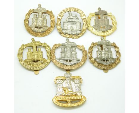 Seven British Army Dorsetshire / Dorset Regiment metal cap badges including a Victorian other ranks example