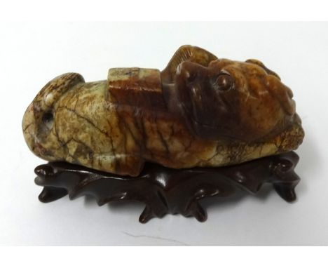 A hardstone or jade carving, in form of a dog and a dragon, on carved hardwood stand.