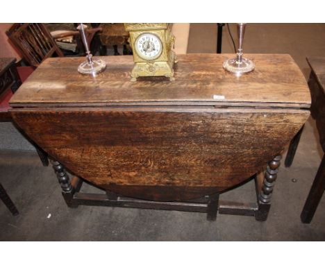 An Antique oak gate leg dining table, fitted single end drawer and raised on turned supports, 117cm