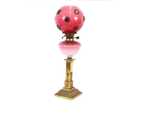 A Victorian table oil lamp, having brass classical stepped column, opaque pink glass reservoir and shade, decorated with colo