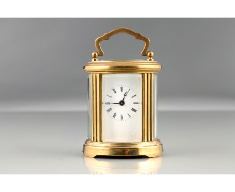 Small brass carriage clock, oval form, rectangular white enamel dial with Roman numerals, bevelled glass, with key. 11cm high