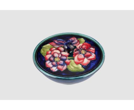 Moorcroft pottery trinket dish and cover, dark blue ground cover decorated with flowers. 16cm diameter 10cm high 