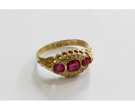 An 18 Carat Gold Ruby and Diamond Ring, three oval cut rubies within a border of rose cut diamonds, in yellow claw settings, 