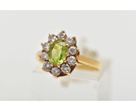 AN 18CT GOLD PERIDOT AND DIAMOND CLUSTER RING, the oval cut peridot, with brilliant cut diamond surrounds, to the openwork ga