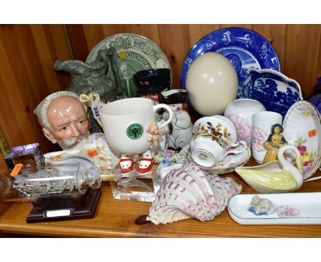 A GROUP OF CERAMIC ORNAMENTS comprising an ostrich egg on a square wooden stand, a Royal Doulton 1910 blue and white Burns wa