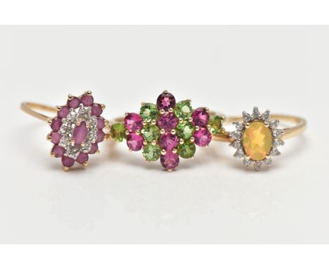 THREE GEM SET RINGS, the first designed as a tiered lozenge shape cluster centring on a marquise cut ruby, within a surround 