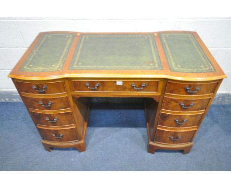 A YEW WOOD KNEE HOLE DESK, with triple green leather writing surface, nine assorted drawers, on bracket feet, length 118cm x 