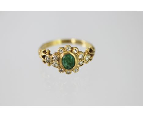 An emerald and diamond 18ct gold ring 1978, designed as a central oval emerald within a surround of twelve brilliant cut diam