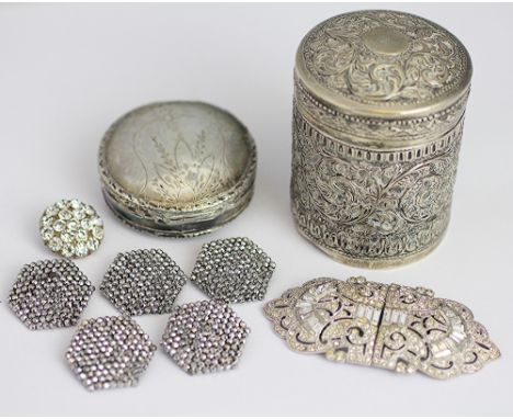 An Indian white metal cylindrical jar and cover, embossed with busy scrolling floral designs, 6.5cm high, along with a white 