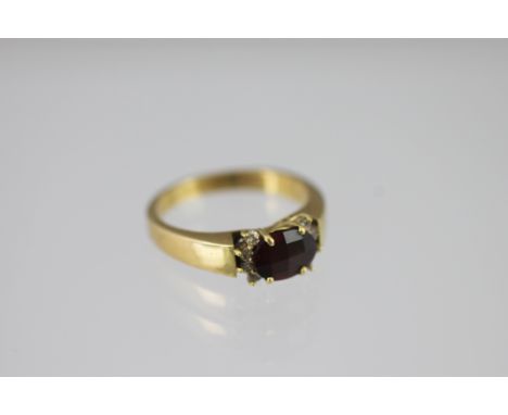 A garnet and diamond set 18ct yellow gold ring 2002, the oval mixed cut garnet within a surround of eight brilliant cut diamo