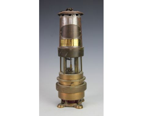 A Naylor Spiralarm brass miners lamp, Type M, by J H Naylor Wigan, with red glass section to base, with presentation label to