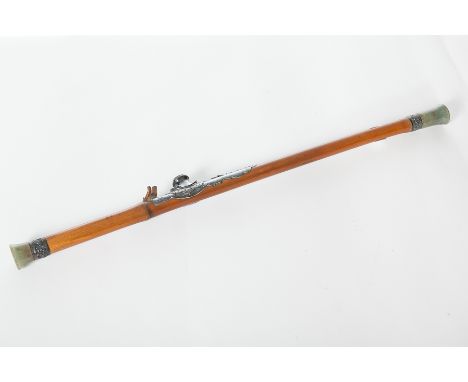 CHINESE BAMBOO OPIUM PIPE
with green hardstone ends and white metal mountings, 62.5cm 