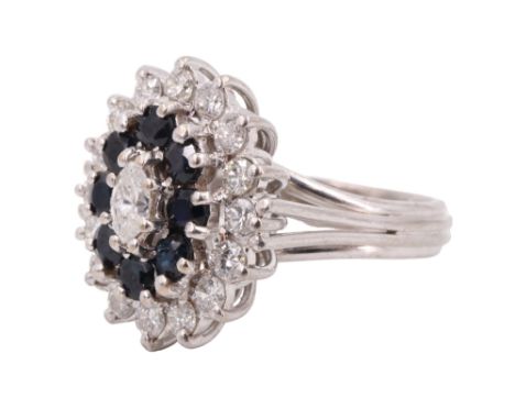 An impressing sapphire and diamond oval cluster ring, comprising a central marquise cut diamond framed by round cut sapphires