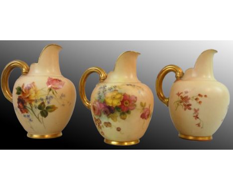 A Royal Worcester blush ivory trio of flat-back jugs, each with gold gilt and floral decoration on apricot ground, green date