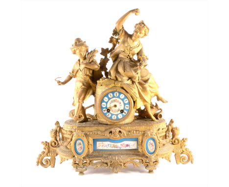 A French gilt spelter mantel clock, with porcelain insets, barrel-shaped mechanism case, modelled with two figures, movement 