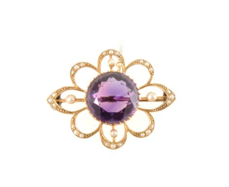 An amethyst and seed pearl brooch, the round faceted amethyst 14mm diameter, claw set in a yellow metal open scalloped frame 