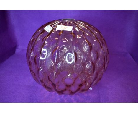 A pink glass light or lamp shade having a wave design