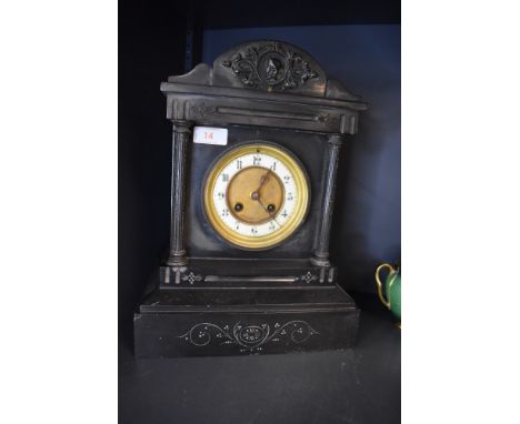 An antique mantle or bracket clock in a Gothic style having solid stone case with brass and enamel face dial