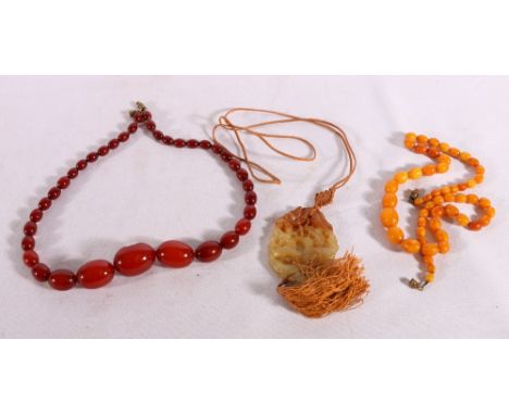 Strand of thirty seven graduated cherry red amber beads, 36g, strand of fifty three graduated amber beads, 16g and a Chinese 