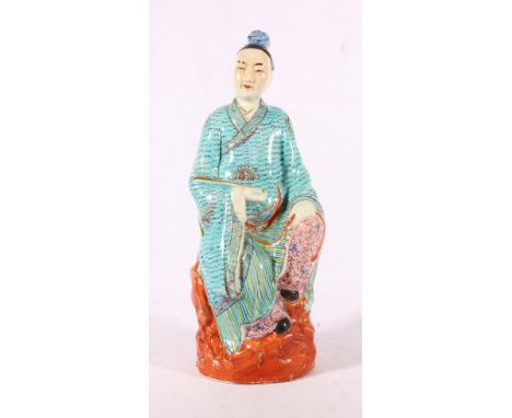 Chinese 20th Century decorated figure of a man holding a scroll, seated on a rock, 37cm, stamped mark to base.