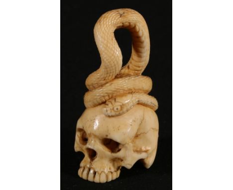 19th century ivory netsuke depicting a skull with a snake curled round the top of the skull, 6cm. Meiji.