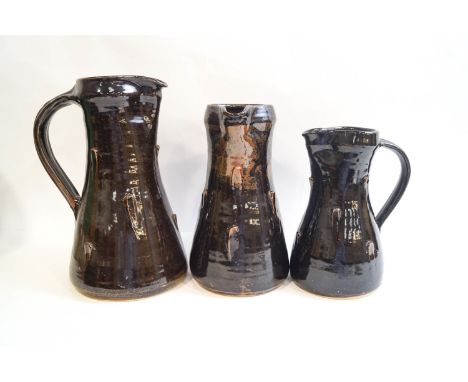 Jeremy Leach (b1941), three Lowerdown pottery stoneware jugs of graduated size, raised decoration with a deep brown glaze, im